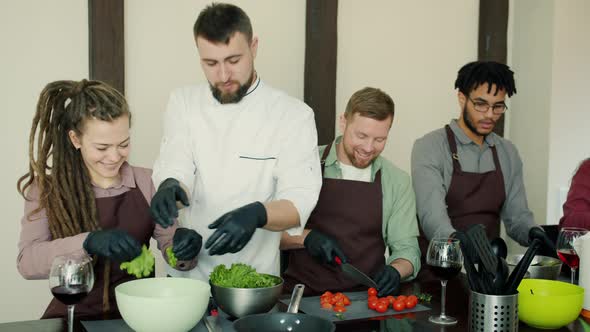 Multi-ethnic Group of Young People Cooking Salad During Cookery Master-class alt