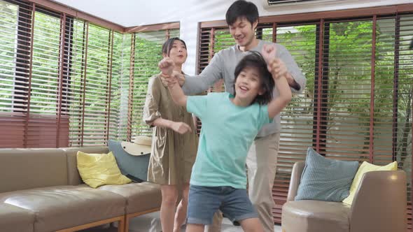 Happiness cheerful asian family dad mom and son funny dancing in living room at home funny moment