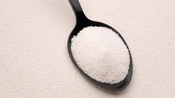 close up collagen powder in spoon on collagen powder background, left rotating alt