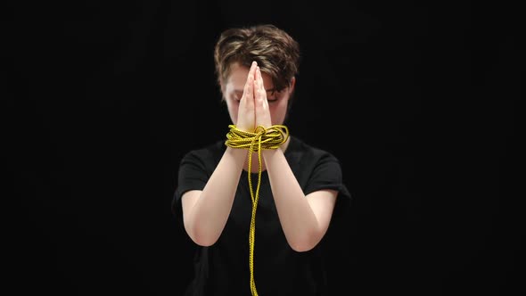 Clasped Female Hands Tied with Rope with Blurred Sad Woman at Background alt