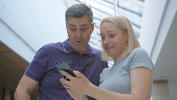 A Man and a Woman are Laughing While Looking at Something Interesting on the Smartphone Screen