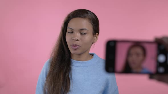 African Blogger Woman Making Online New Video Blog Vlog with Her Smartphone on Pink Background alt