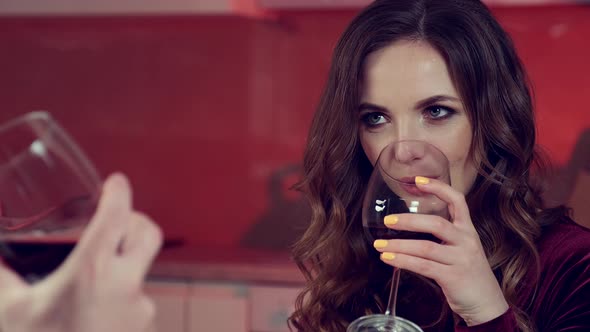 Young Woman with Evening Makeup Drinking Wine in the Kitchen with Her Husband