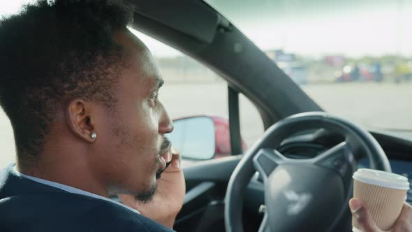 Businessman in Stylish Suit Talking on Mobile Phone While Sitting in Luxury Car alt