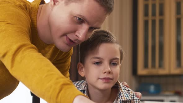 Caucasian father explaining task of homework to son with tablet computer