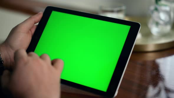 Adult Hand Swiping Green Tablet Screen Closeup alt