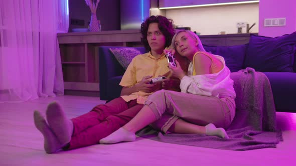 Young Cheerful Caucasian Husband and Wife Play Videogames Against Each Other at Home Enjoying alt