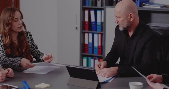 Manager Signing Reports in Meeting with Colleagues alt