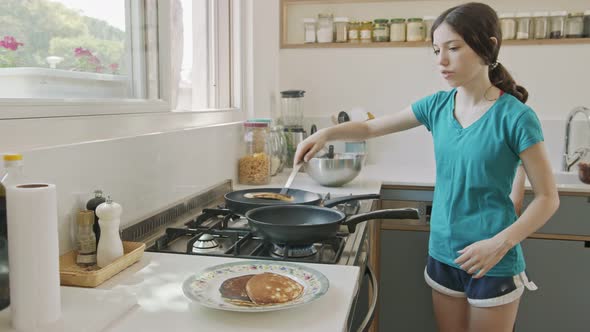 Young kids preparing pancakes in the kitchen using a frying pan alt