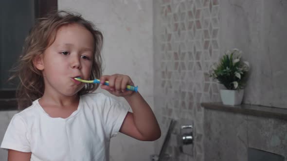 Little Child Girl is Brushing Her Teeth with Toothbrush in Bathroom