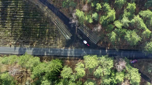 Flying above a tractor transporting cut timber from the forest alt