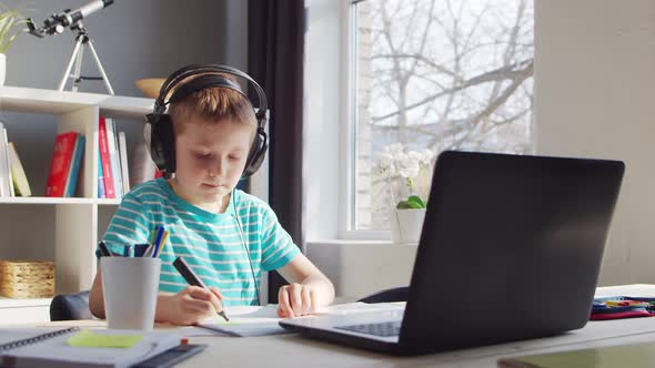 Boy is Doing  Homework at the Table. Cute Child is Learning at Home. alt