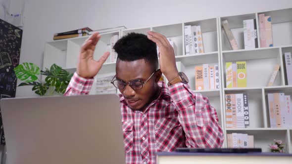 African man working from home feeling serious with laptop alt