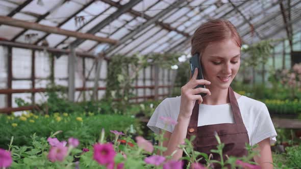 Close Up Portrait of Beautiful Joyful Female Florist Store Manager Talking on Cellphone About Plant