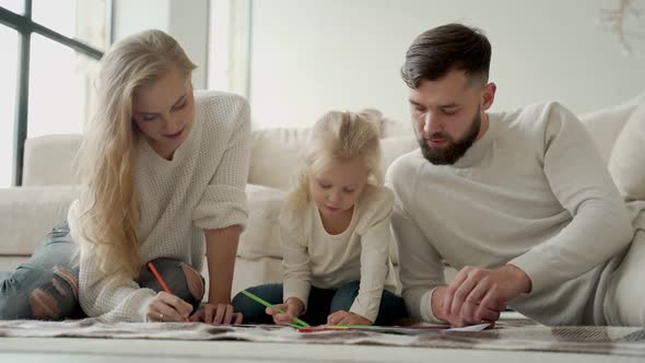 Young Family a Married Couple with a Small Charming Daughter Lying on the Floor in a Modern House alt