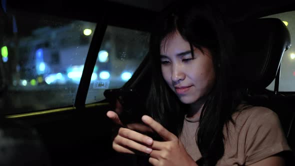 Asian young woman using smartphone in a car, checking mails, chats or the news online.