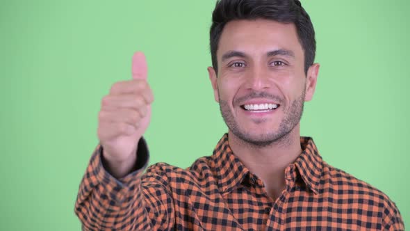 Face of Happy Young Hispanic Hipster Man Giving Thumbs Up alt
