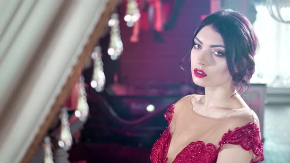 Fashionable Caucasian Beautiful Female Model in Sexy Red Dress Posing at Luxury Vintage Interior alt