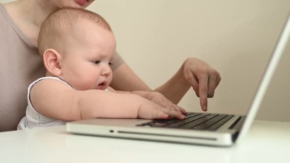 Close Up Portrait Little Baby Boy Funny Facial Expression Sitting on Mother's Lap Studying Laptop