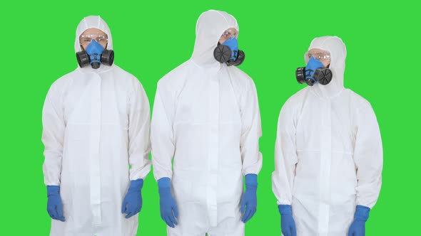 Team of Scientists or Doctors in Protective Suits Ready for Work Crossing Hands on a Green Screen alt