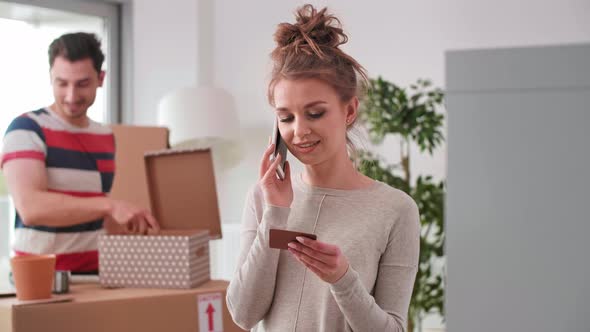 Smiling woman using phone while moving house  alt