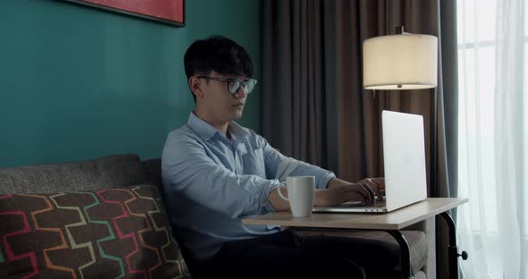 Attractive Asian Vietnam Man Busy Work Computer or Smart Tablet on Laptop at Home in Freelance Data alt