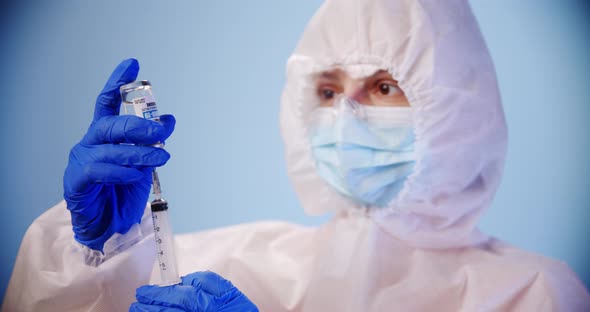 Blured Doctor or Nurse Wearing Personal Protective Equipment and Begins To Fill the Vaccine Into the alt