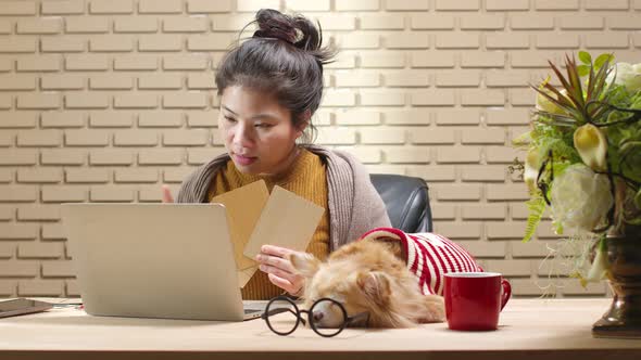 Asian female woman using laptop computer online meeting work at home while her dog sleep nearby alt