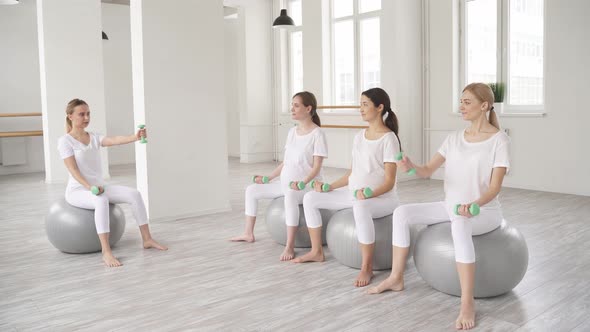 Group of Pregnant Females Sit on Fitballs Training with Dumbbells
