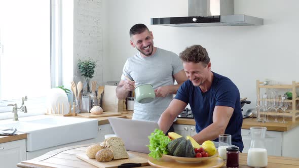 Lovely gay couple talking together while doing daily morining routines in kitchen at home