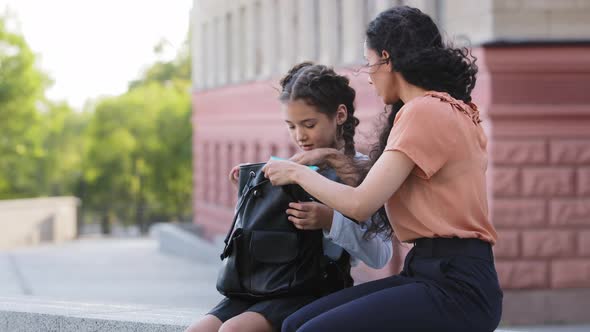 Hispanic Family Little Cute Girl Daughter Child Schoolgirl with Mom Mommy Sitting Outdoors Talking alt