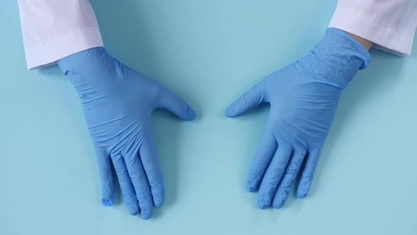 Doctor's Hands in Medical Gloves Shows the Symbol of the Heart on Blue Background with Copy Space alt