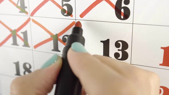 Female Hand Crosses with Red Marker the Calendar Day 13. Slow Motion Shot. Close Up