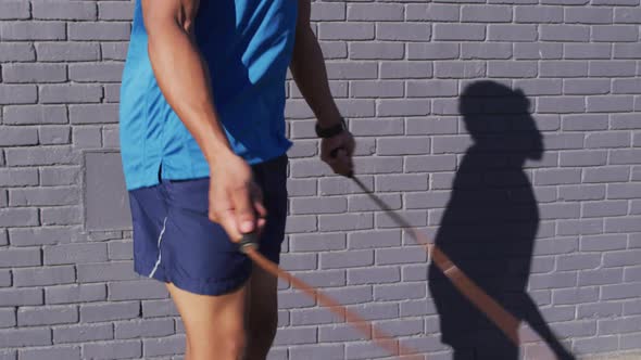 Fit african american man exercising in city, skipping with skipping rope in street alt