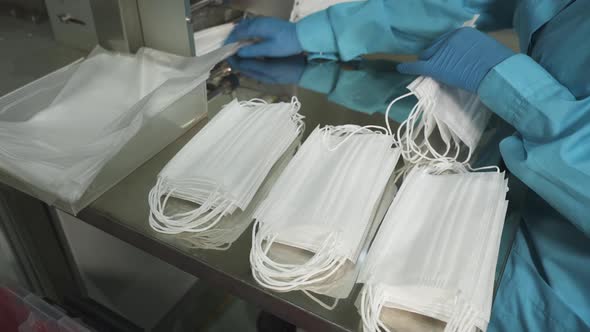 Factory worker collecting face masks into stacks. Medical supply production alt