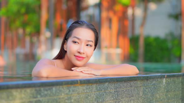 Young asian woman enjoy around outdoor swimming pool for leisure alt