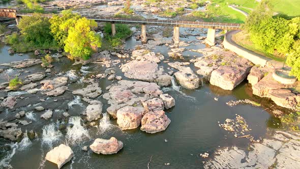 Bird view over Falls Park in Sioux Falls, South Dakota, with railroad bridge spanning river.