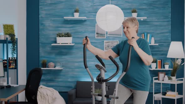 Mature Woman Using Stationary Bicycle to Do Physical Exercise alt