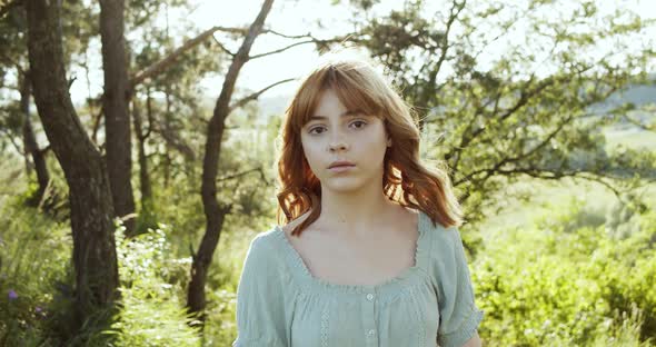 Attractive European Chestnut Teen Girl with Natural Makeup Looks Into the Camera in Nature on a alt