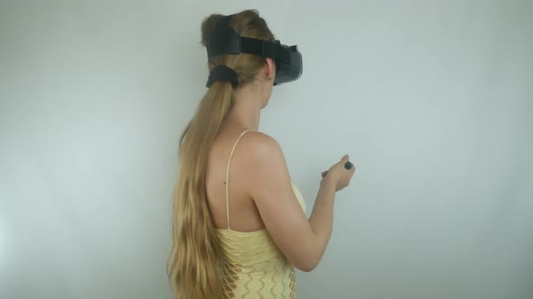 Beautiful Woman Uses A Helmet Of Virtual Reality And A Gamepad In A Simulation Game