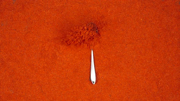 Spoon with a red pepper powder falls on a red pepper powder