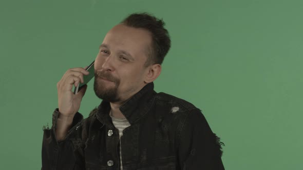 A Man is Talking Cheerfully and Embarrassedly on Mobile Phone on the Chroma Key alt