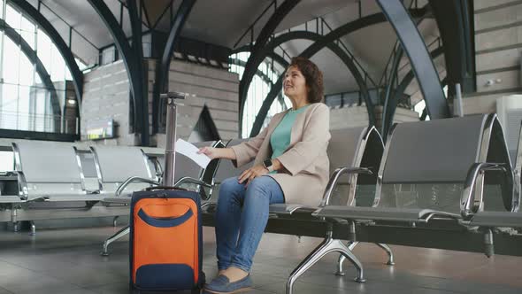 Mature Female Tourist Waiting for Train Departure Sitting with Luggage and Ticket at Railway Station alt
