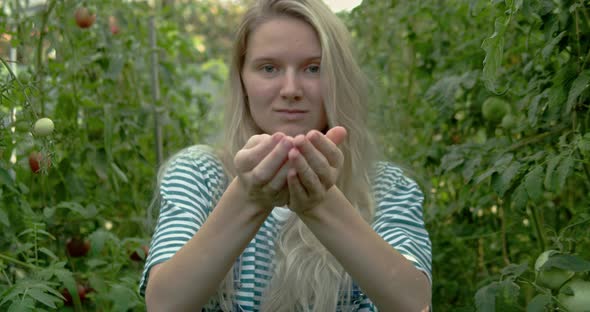 Young Caucasian Woman Shows Tomatoes in Her Hands to the Camera