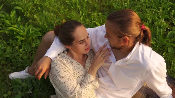 A Woman Lies on the Lap of a Man in Nature Romantically Straightens His Hair
