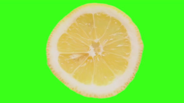 A Closeup of a Lemon Cyclically Rotates on a Highlighted Green Background