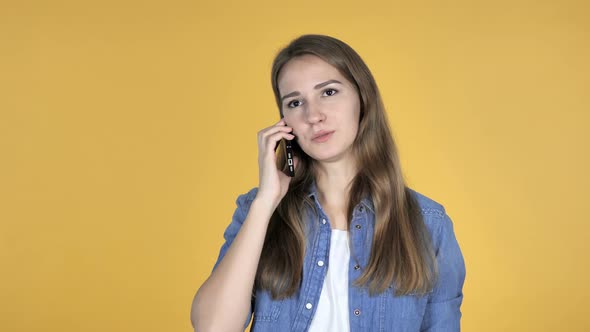 Pretty Woman Talking on Smartphone Isolated on Yellow Background alt