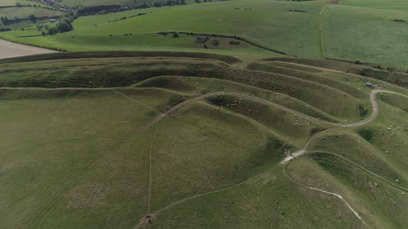 An aerial that tracks forward over Maiden castle towards the western gate which pans down as it appr alt