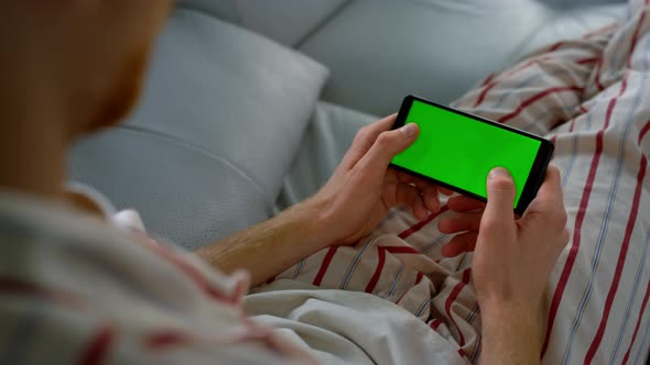 Man Typing Green Screen on Smartphone at Home alt