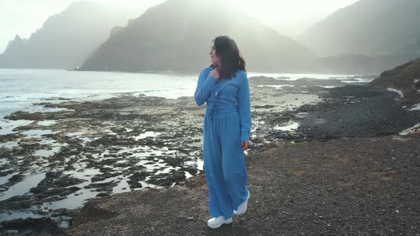 A Woman Walks Next to the Ocean Enjoying the Calm Scenery Against the Background of the Volcanic alt
